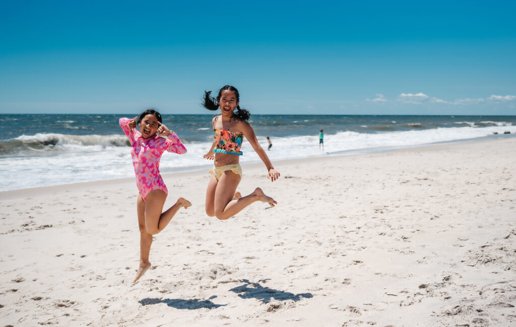 Two girls jumping in the air at a beach