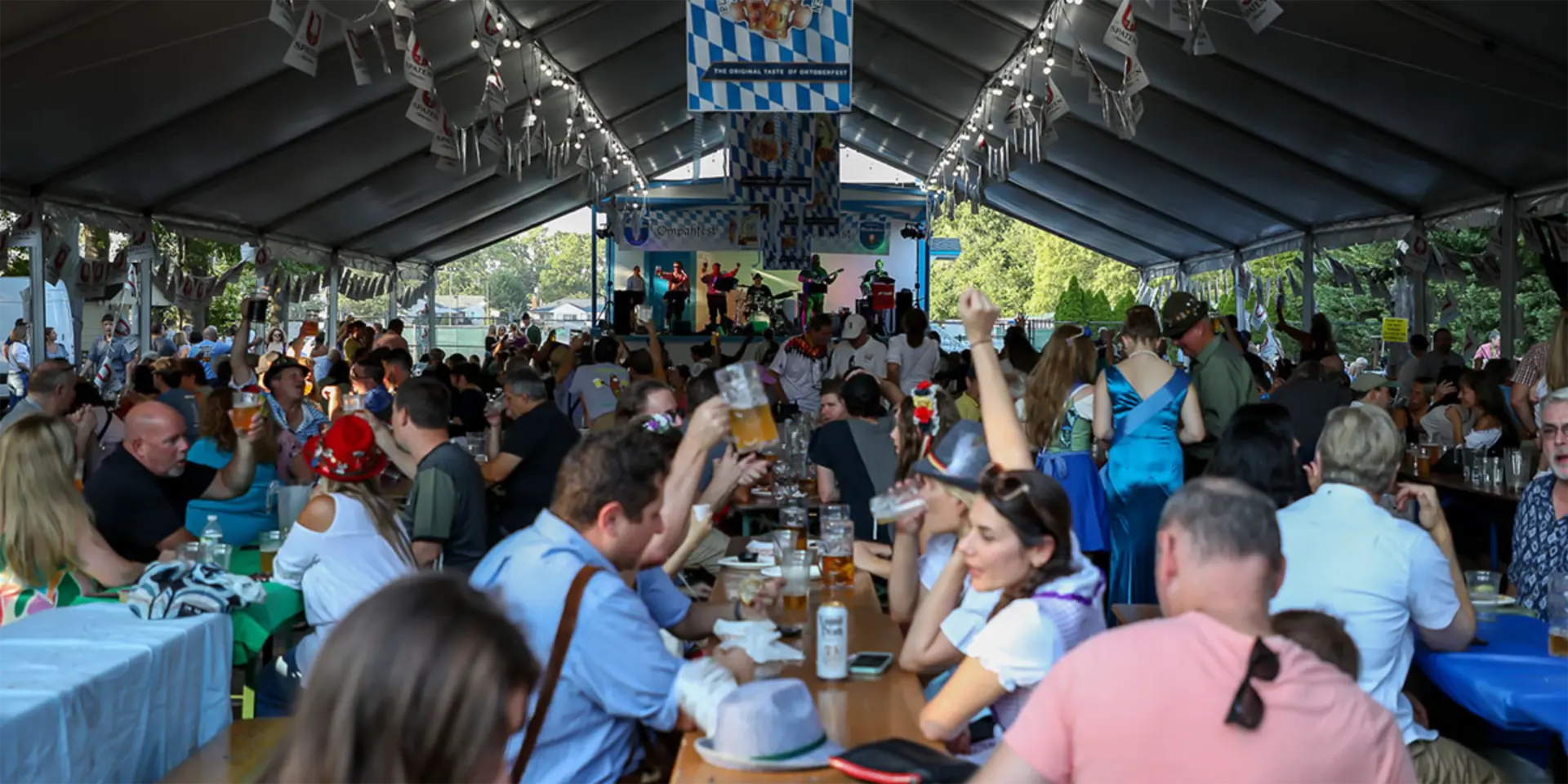 Crowd enjoying beer while seated at a lively Long Island Oktoberfest celebration.