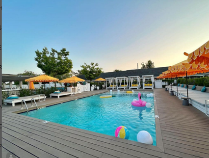 Capri Southampton hotel pool with floating beach ball, flamingo float, and orange sun umbrellas