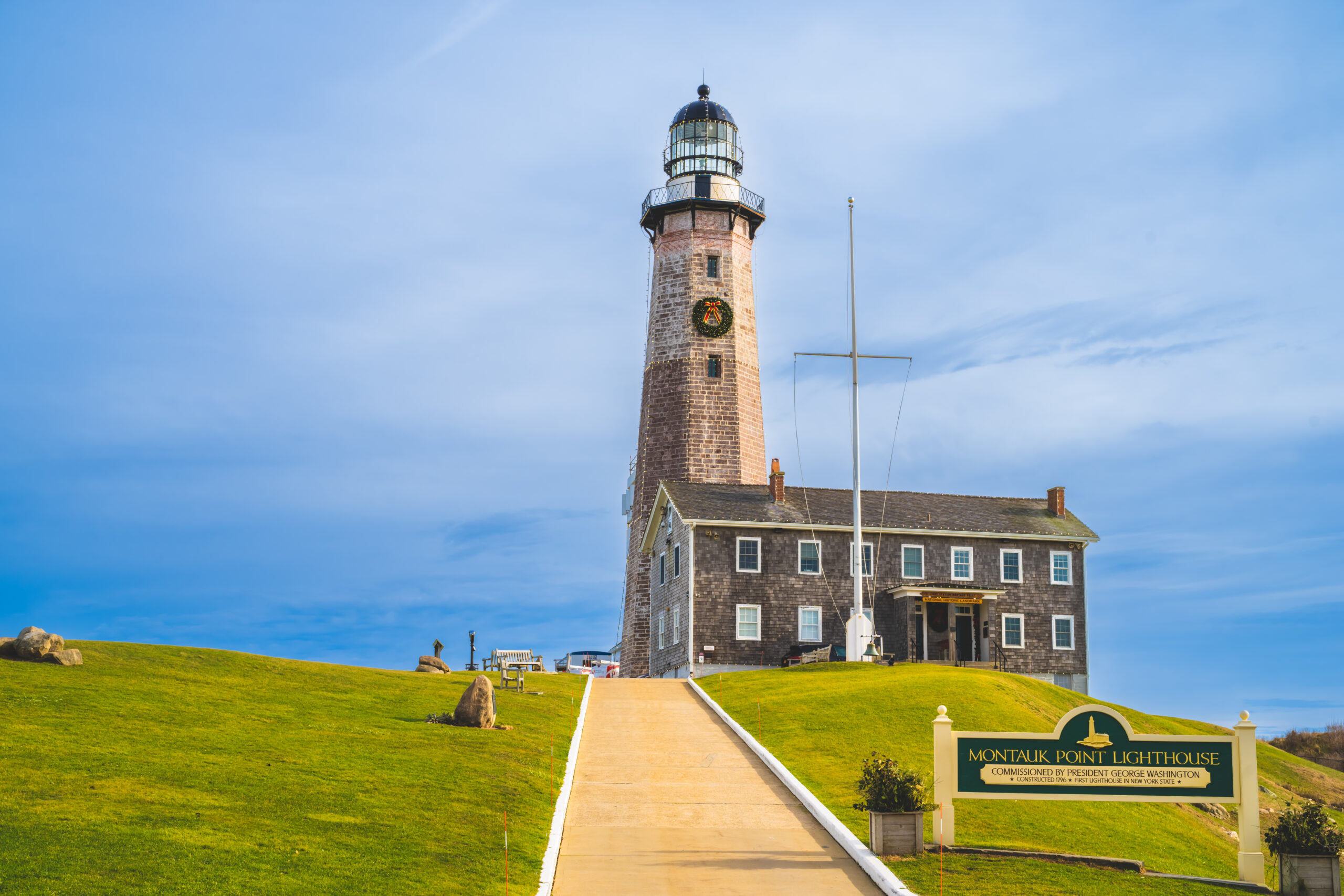 Montauk Point Lighthouse with blue sky and manicured yellow-green grass