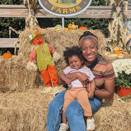 Mom and child sitting on hay bale at a farm