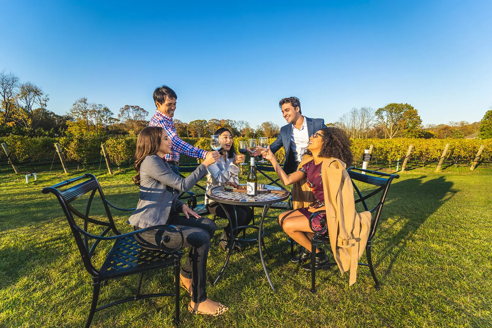 Friends enjoying wine at a Long Island vineyard picnic table
