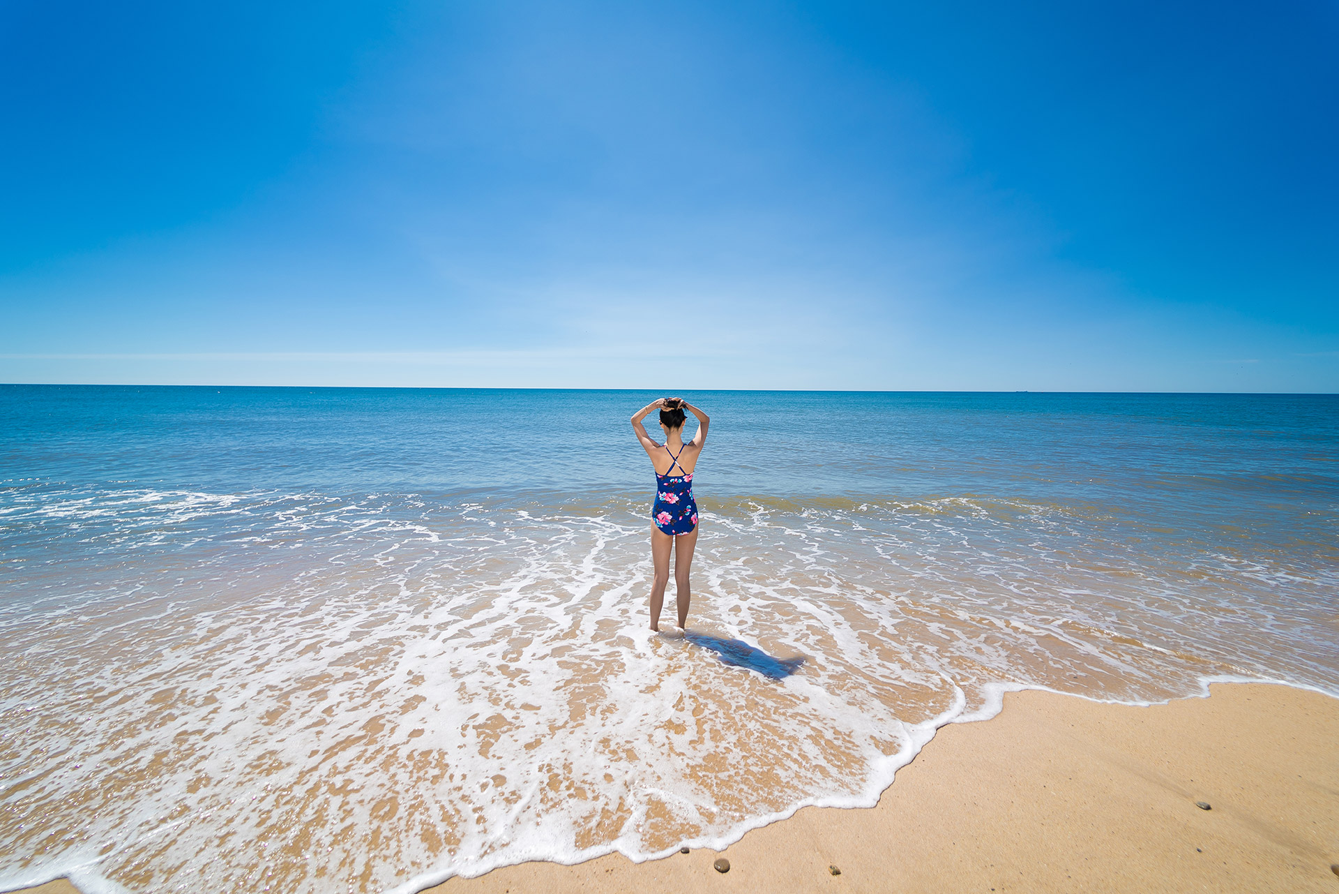 Person standing on a quiet beach shoreline in the Hamptons, Long Island