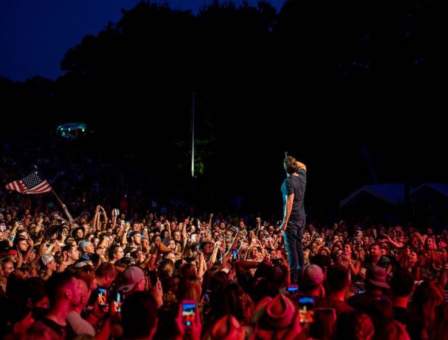Man on stage surrounded by a crowd of people at a concert