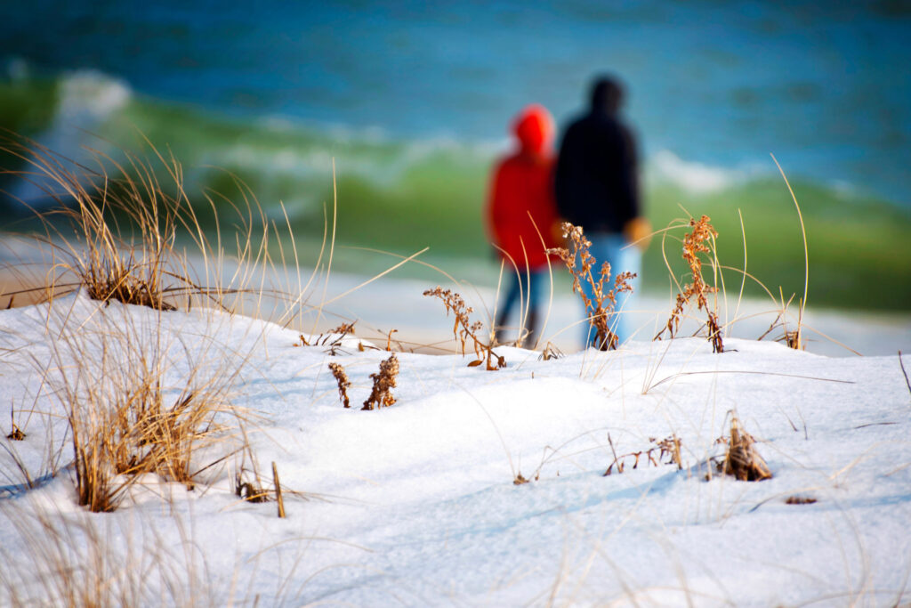 Couple walking along a snowy beach dune on Long Island in winter