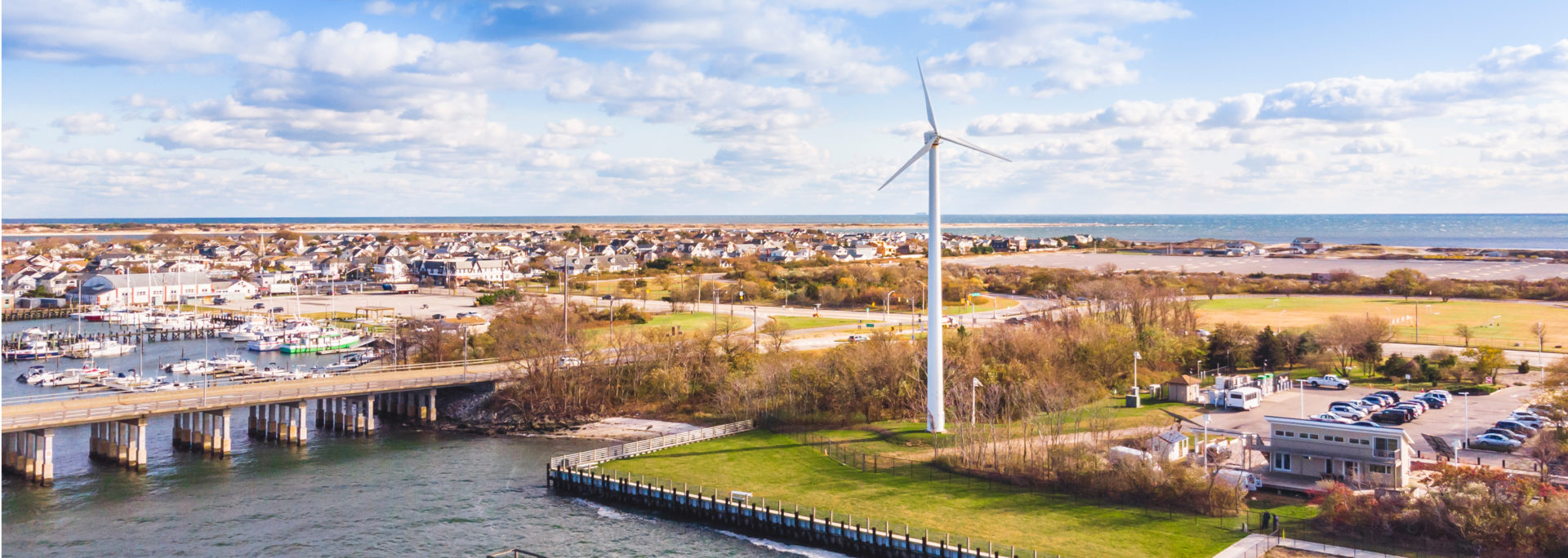 Aerial view of a wind turbine and waterfront town on Long Island