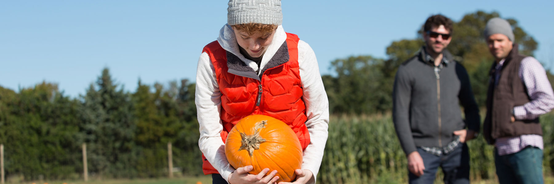Visitor holding a pumpkin at a Long Island farm in fall