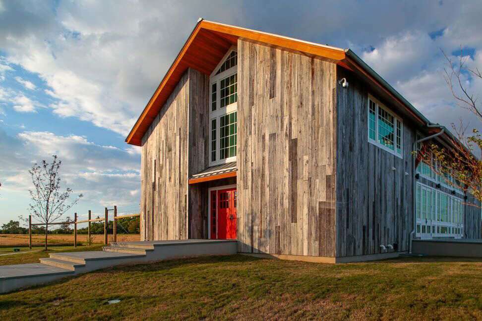 Photo of Kontonska Winery. A rustic barn style with a red door and large glass windows on the right wall.