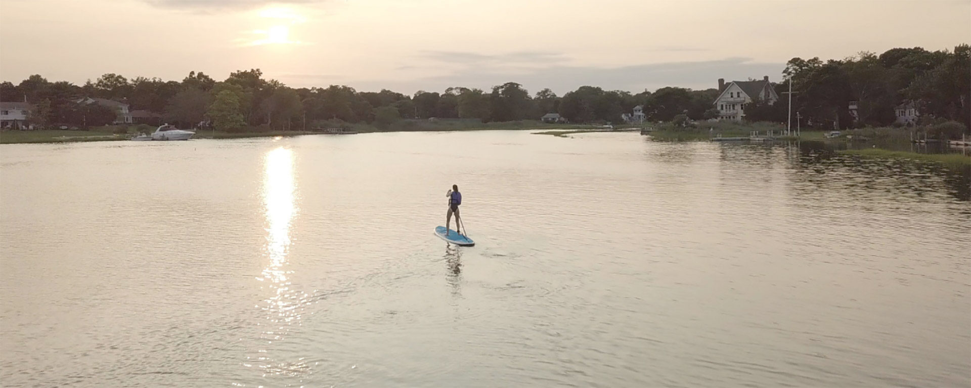 Paddleboarder gliding across calm water on Long Island